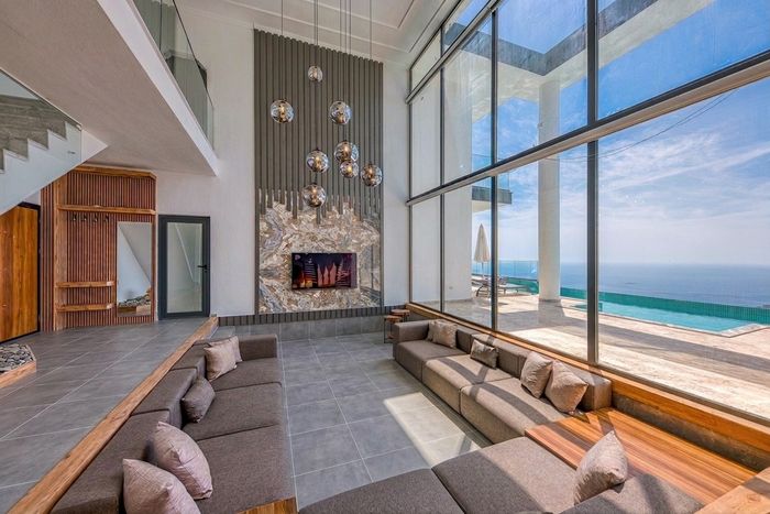 Large-format grey porcelain floor in a bright open-plan villa living room with sea-view windows
